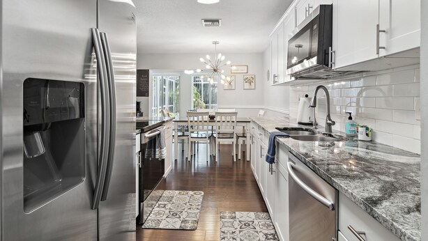 A modern kitchen with stainless steel appliances, white cabinetry, and a central island with seating.
