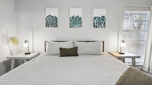 A neatly arranged bedroom with a large bed, two bedside tables, and three wall-mounted artwork pieces.