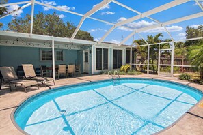 A swimming pool with a covered patio area, lounge chairs, and a view of the surrounding greenery. - Paradise Bliss! Heated Pool, Near Boat Ramp, Beaches, & Golf Course,Wifi (Sebastian)