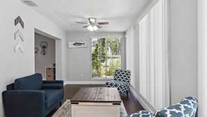 A living room with a dark blue sofa, patterned armchair, and a wooden coffee table.