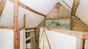 Eine Holztreppe führt zu einem Erker mit freiliegenden Backsteinwänden und einem Gemälde.