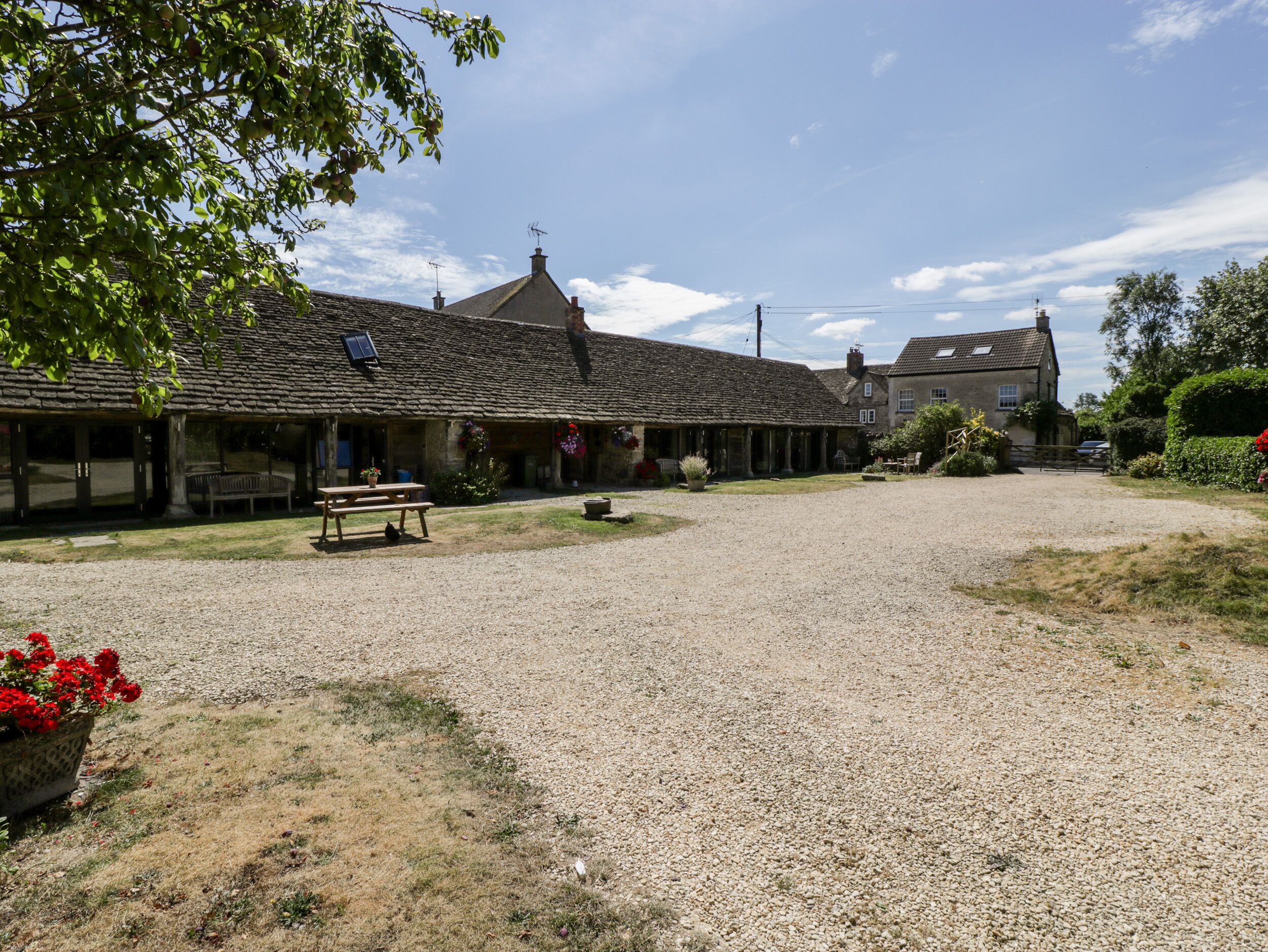 A building with a gravel driveway, a picnic table, and a bench.