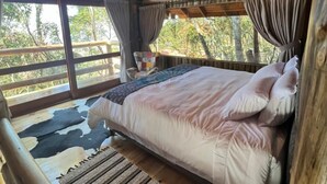 A wooden cabin bedroom with a bed, curtains, and a hanging light fixture. - Pousada Parador 33 (Biguacu)