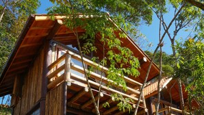 A wooden cabin with a balcony, surrounded by trees. - Pousada Parador 33 (Biguacu)