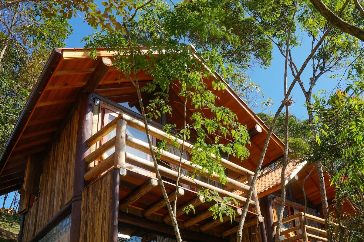 A wooden cabin with a balcony, surrounded by trees.