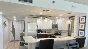 Une cuisine moderne avec des meubles blancs, des appareils en acier inoxydable et un îlot central doté de tabourets de bar.