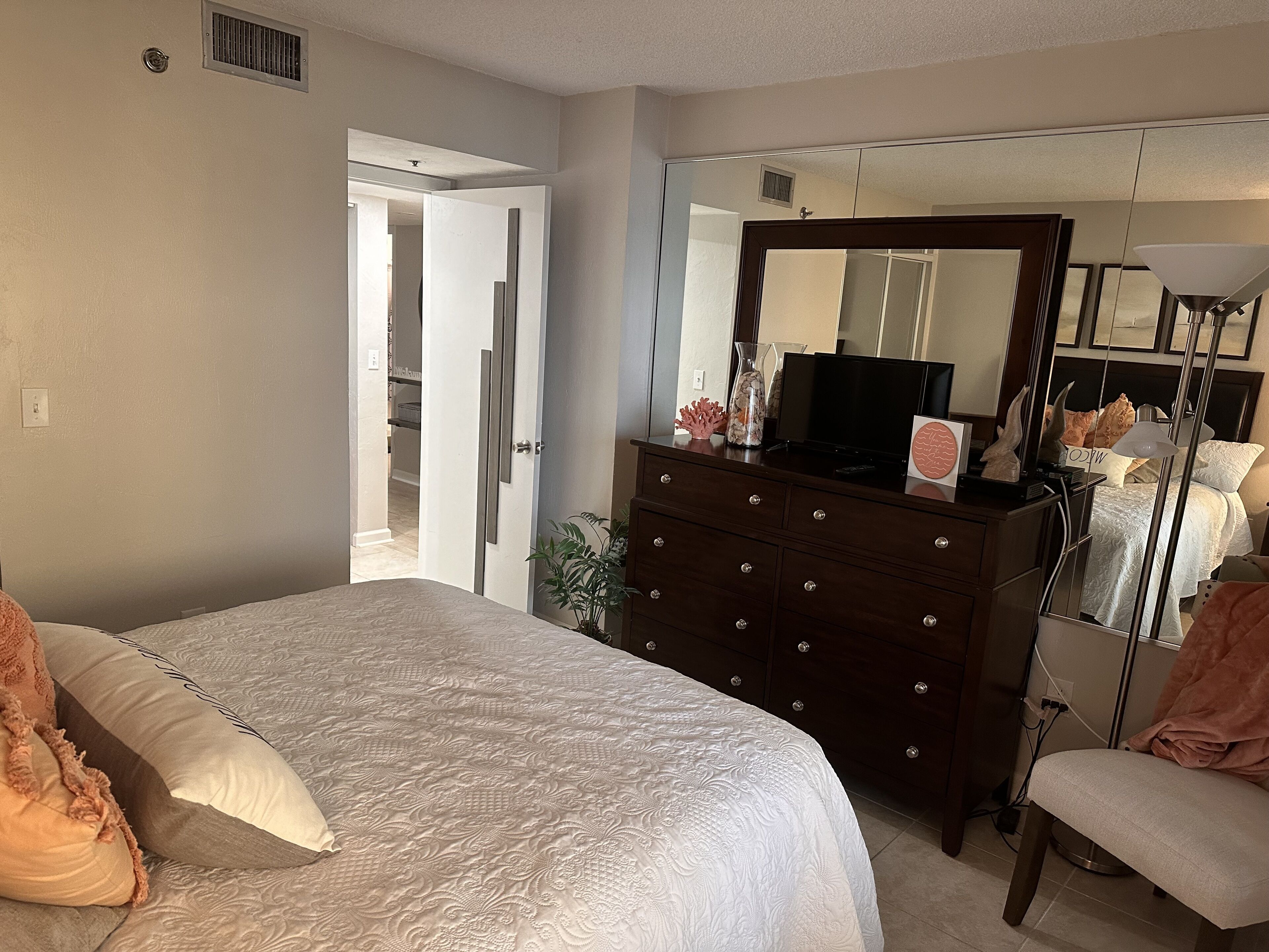 Une chambre à coucher avec un grand lit, une commode, un miroir et une chaise.