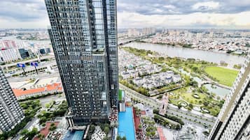 Un immeuble de grande hauteur doté d’une façade moderne en verre, d’une piscine et d’un espace paysager offrant une vue sur la rivière.