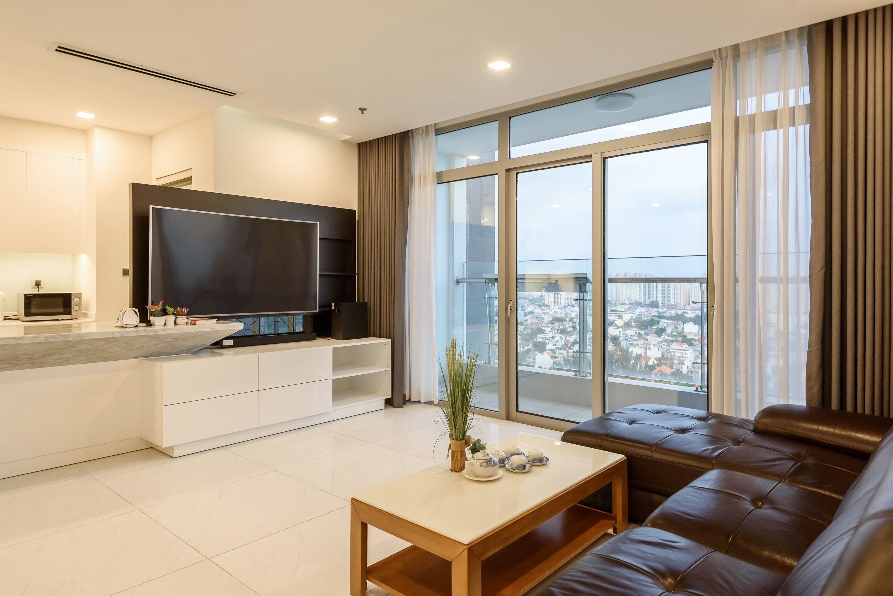 Una sala de estar moderna con un televisor grande, un sofá y una mesa de comedor.