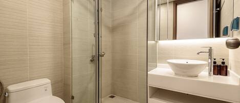 A modern bathroom with a glass-enclosed shower, a white sink, and a toilet.