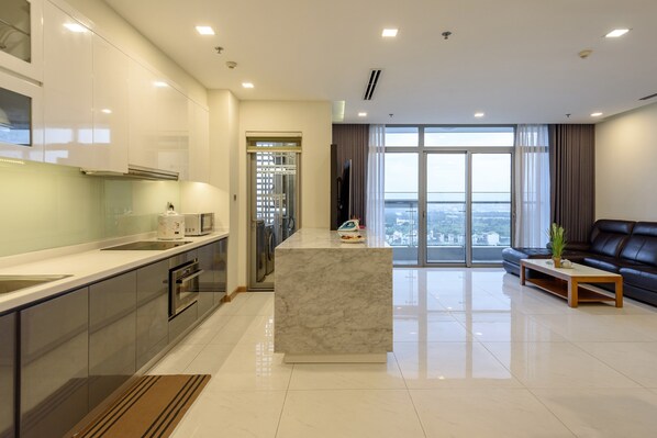Una cocina moderna con una isla de mármol, electrodomésticos de acero inoxidable y un amplio ventanal con vistas a la ciudad.