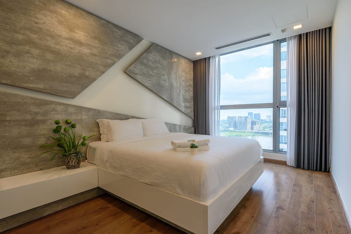 Ein modernes Hotelzimmer mit einem großen Bett, Blick auf die Stadt und minimalistischem Design.