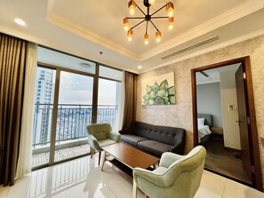 Una sala de estar moderna con un sofá, dos sillones, una mesita de centro y un ventanal con vistas a la ciudad.
