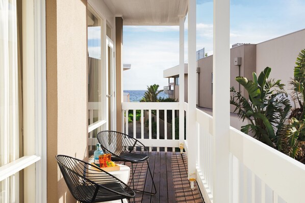 A balcony with two chairs, a table, and a bottle of water.