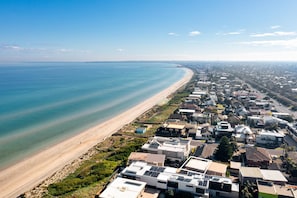 A coastal residential area with a beachfront, houses, and a clear sky. - Rest Ashored Direct Beach Access (Aspendale)