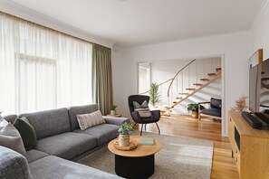 A modern living room with a grey sofa, a round coffee table, and a staircase leading to another level.