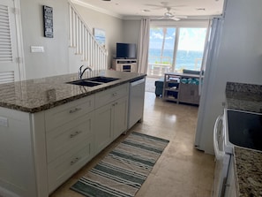 Enjoy ocean views from the kitchen window, where a sink and stainless steel range hood meet white cabinetry.