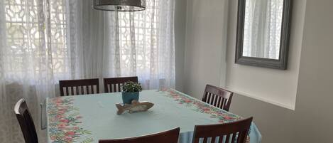 Een eetgedeelte met een tafel gedekt voor zes personen, omringd door houten stoelen, een potplant en een decoratieve vis op tafel.