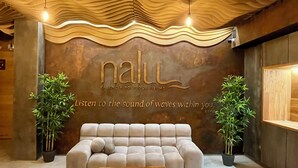 A modern interior with a textured ceiling, a plush sofa, and two potted plants. - Nalu Valencia Boutique Rooms (Valencia)