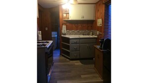 Una cocina compacta con armarios de madera, una encimera y una estufa.