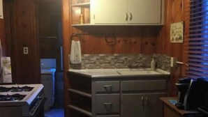 Una cocina compacta con armarios de madera, una encimera y una estufa.