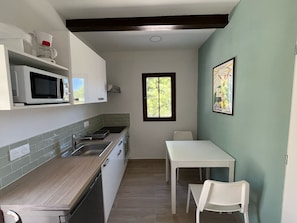 A compact kitchen with a microwave, sink, and a small dining table with chairs.
