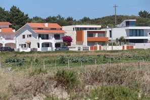 A residential area with modern houses, a garden, and a field in the foreground. - Casa do Cipreste - In front of the beach (Chafé, Viana do Castelo)