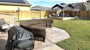 A backyard with a covered patio area, outdoor seating, and solar panels on the roof.