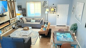 A living room with a fireplace, sofas, a dining table, and a kitchen area.