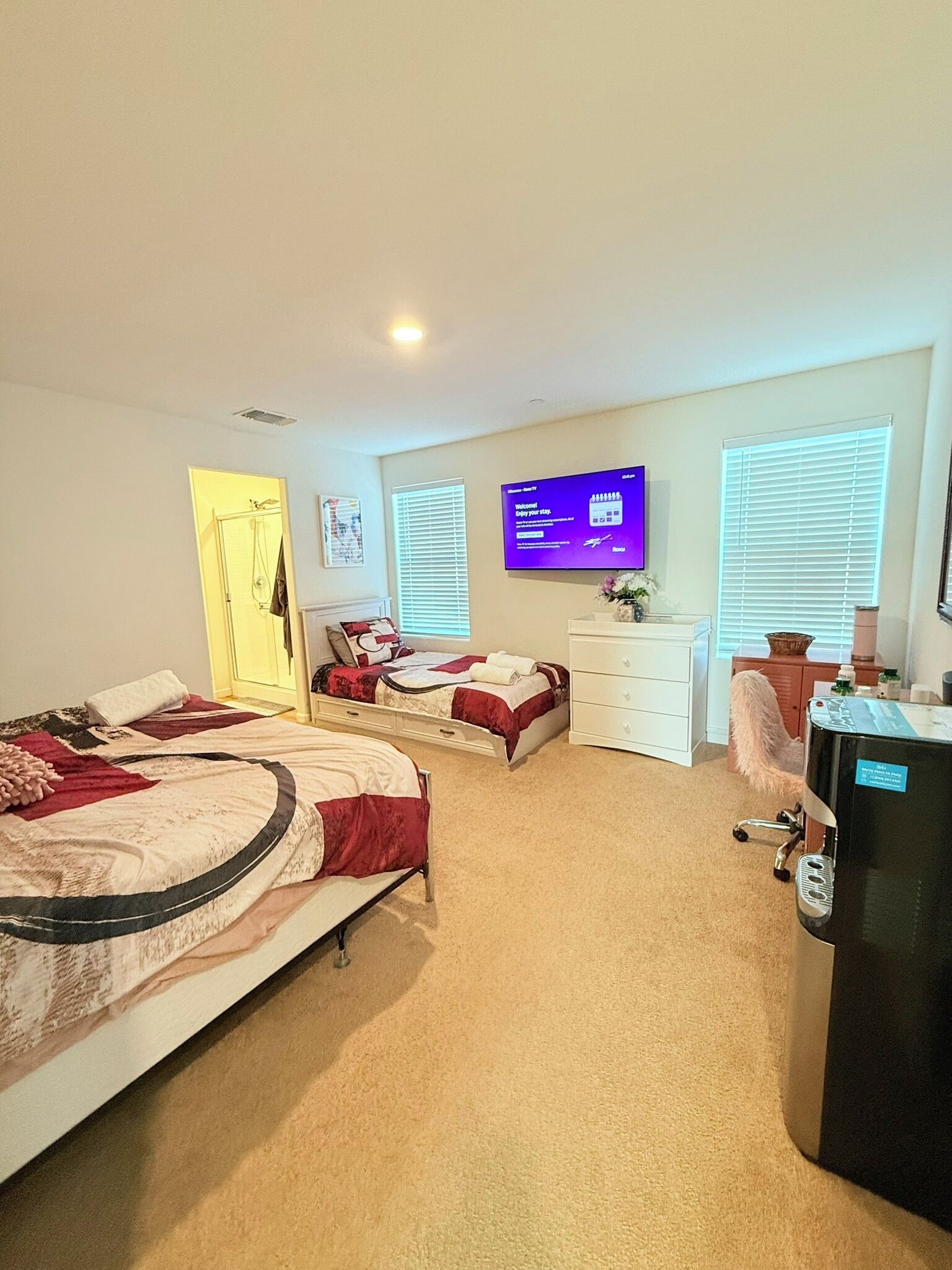 Une chambre d’hôtel avec deux lits, un bureau, une télévision et un minibar.