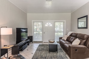 Relax in this stylish living room with a large flat-screen TV, comfortable sofa, and patterned rug.