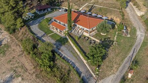 An aerial view of a property with a main building featuring a red-tiled roof, a secondary structure with a blue roof, and a small annex. - Medusa Rooms (Kassandra)