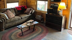 Ein gemütliches Wohnzimmer mit einer Ledersofa, einem Couchtisch, einem Fernseher und einer Lampe.
