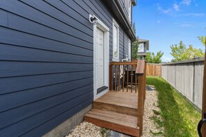 A house with a dark siding exterior, a wooden front porch, and a white door. - Modern, cozy and private suite basement in South West Edmonton (Edmonton)