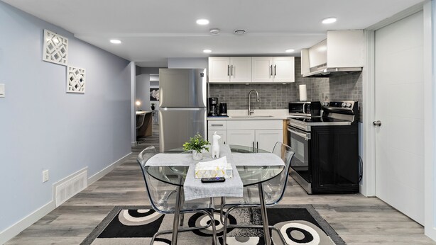 Una cocina compacta con electrodomésticos modernos, una mesa de comedor con sillas y una pequeña planta en maceta.