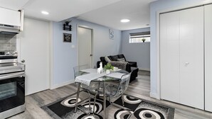 Una cocina compacta con mesa de vidrio, horno empotrado y un pequeño rincón comedor con sofá.
