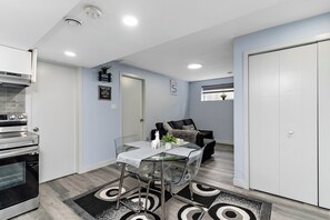 Eine kompakte Küche mit Esstisch mit Glasplatte, einem Einbauofen und einer kleinen Essecke mit einer Couch.