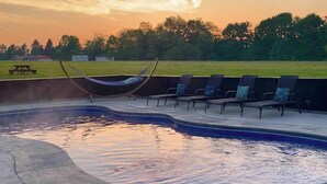 A swimming pool with a curved edge, a hammock, and lounge chairs. - The Aviator’s Lounge, loft living in the NRG, private pool & hot tub (Fayetteville)