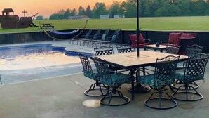 An outdoor patio with a pool, seating, and a large umbrella. - The Aviator’s Lounge, loft living in the NRG, private pool & hot tub (Fayetteville)
