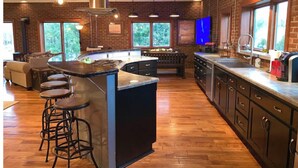 A modern kitchen with a central island, bar stools, and a large window. - The Aviator’s Lounge, loft living in the NRG, private pool & hot tub (Fayetteville)