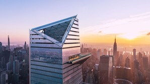 A modern skyscraper with a unique angular design, featuring a glass facade and a rooftop terrace.