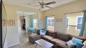 A living room with a brown sectional sofa, a small wooden coffee table, and a ceiling fan.