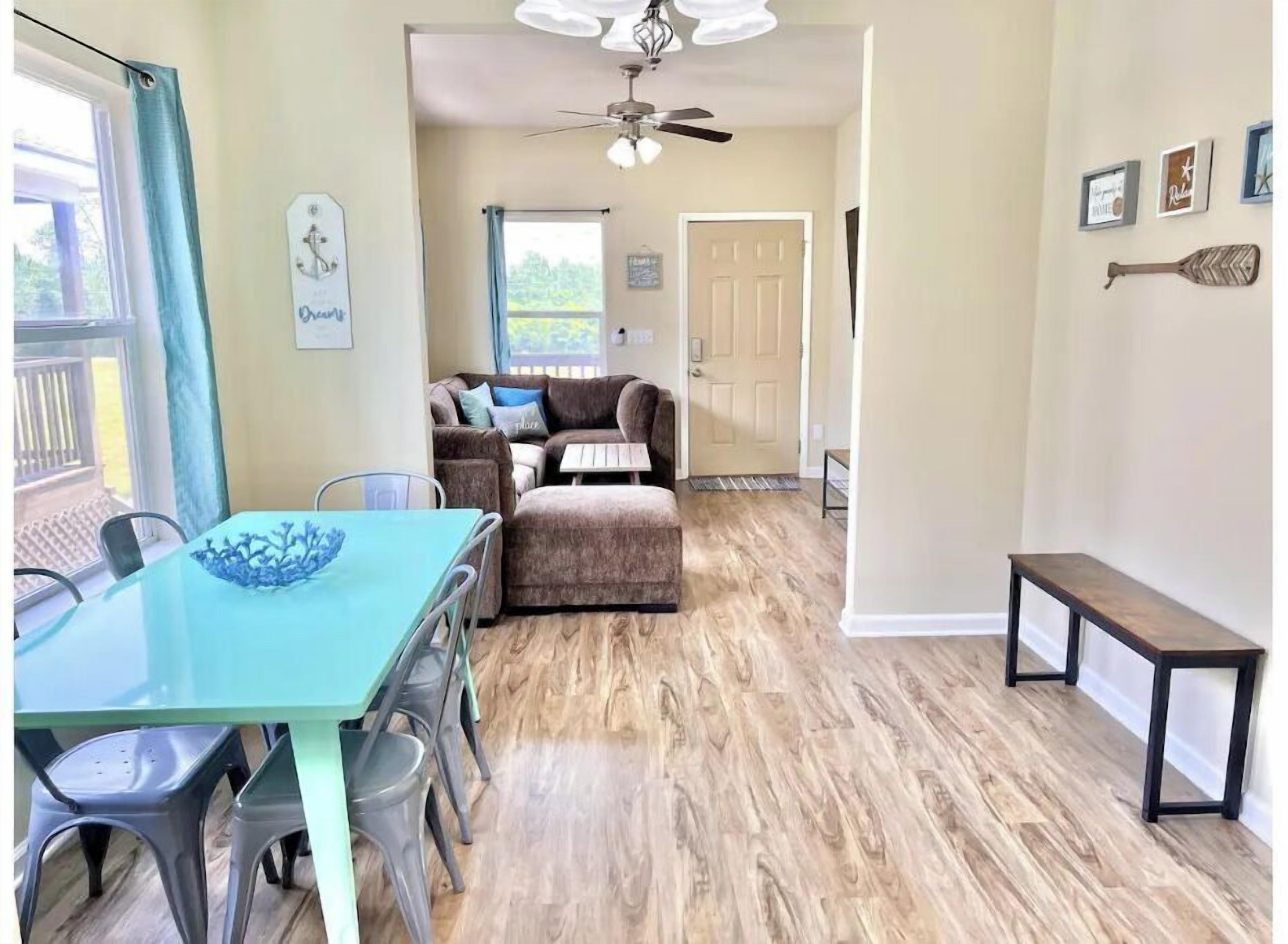 A cozy living area with a dining table, chairs, a sofa, and a ceiling fan.