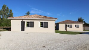 Two single-story buildings with tiled roofs, beige walls, and gravel driveways. - Gîte Rose, Relaxation and well-being for all the family (Fontenay-le-Comte)