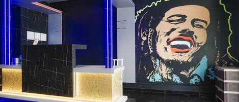 Uma área de recepção com design moderno, com balcão de atendimento, parede com um grande mural e detalhes de iluminação azul.