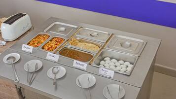 Un bufé de desayuno con opciones de comida señalizadas y utensilios para servir.