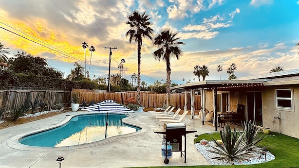 Un cortile con piscina, barbecue e una veranda coperta.