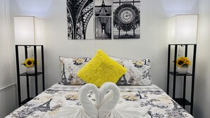 Un lit recouvert d’une couvre-lit à motifs floraux, un oreiller jaune et deux lampes murales décorées de motifs de tournesols.