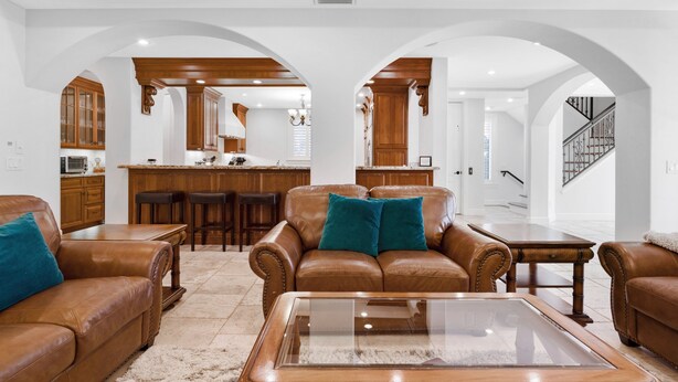 Ein geräumiges Wohnzimmer mit Ledersofas, einem Glastisch und Holzschränken im Hintergrund.