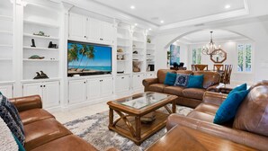 Ein geräumiges Wohnzimmer mit Ledersofas, einem Glastisch und weißen Schränken.